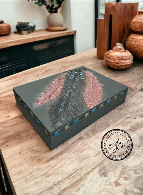 Bluish gray painted box makeover with hand-painted black and red fathers on top, along with a hand-painted string of blue and green beads on the feathers and around the rim of the box.