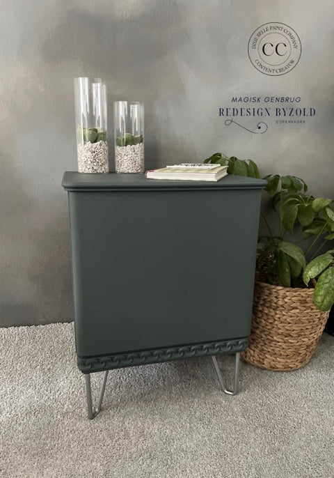 Bluish gray cabinet transformation with metal feet. Staged with two clear tall vases containing pebbles and faux succulents and a cookbook placed on top.