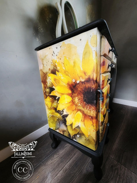 A vibrant and artistically painted dresser showcasing a bold Sunny Daze A1 Rice Decoupage Paper motif, set against a moody, dark background which accentuates the bright floral design.