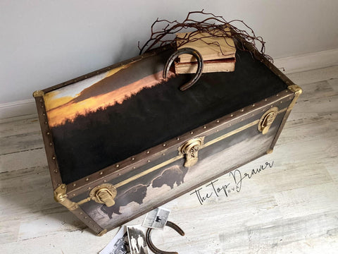 Belles and Whistles Tatanka - A1 Rice Decoupage Paper is a simple way to visually enhance any surface of your project! Large chest with leather on the edges and gold hinges and clasps. The Tatanka Rice Decoupage Paper has been applied to the top of the chest. There is newspaper clippings on the floor in front of the chest along with a rusty horseshoe.