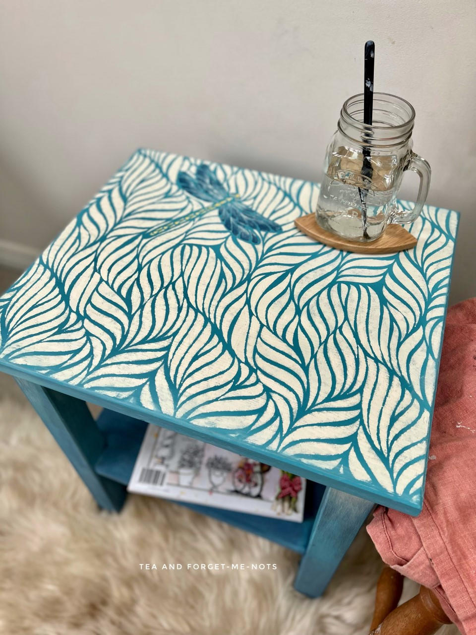 Blue Moon Terra Clay Paint provides endless possibilities for your imagination and can be used on wood, canvas, tile, fabric and more!
Top of side table using Blue Moon Terra Clay Paint as the base color to the  Enchanted Garden - Stencil that was used on top in white.Staged with a mason jar cup with a black straw inside.