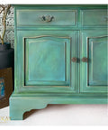 Blue Moon Terra Clay Paint provides endless possibilities for your imagination and can be used on wood, canvas, tile, fabric and more!
A green vanity with Blue Moon Terra Clay Paint and some gray to give it a smokey effect. Staged with black vase and bronze picture frame.