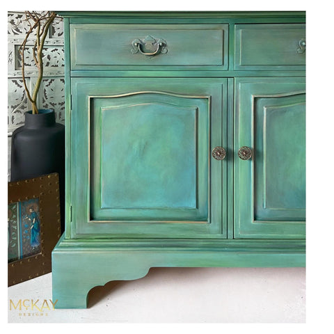 Blue Moon Terra Clay Paint provides endless possibilities for your imagination and can be used on wood, canvas, tile, fabric and more!
A green vanity with Blue Moon Terra Clay Paint and some gray to give it a smokey effect. Staged with black vase and bronze picture frame.