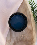 Blue Moon Terra Clay Paint provides endless possibilities for your imagination and can be used on wood, canvas, tile, fabric and more!
Top view of an opened container of Blue Moon Terra Clay Paint staged on top of wooden bowl , greenery and a sheer pink linen.