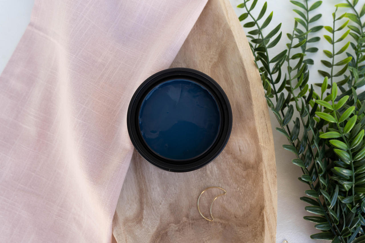 Blue Moon Terra Clay Paint provides endless possibilities for your imagination and can be used on wood, canvas, tile, fabric and more!
Top view of an opened container of Blue Moon Terra Clay Paint staged on top of wooden bowl , greenery and a sheer pink linen.