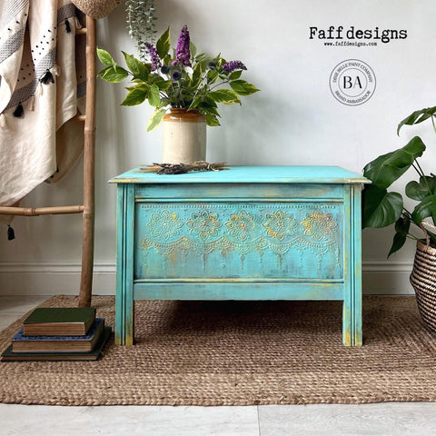 Cerulean Blue Terra Clay Paint provides endless possibilities for your imagination and can be used on wood, canvas, tile, fabric and more!
Coffee table painted in Cerulean Blue Terra Clay Paint with the Lotus Bloom - Stencil on the front panel with gold is dripping off stencil. Gold is used as an accent on the entire piece. Staged with potted plants and books.