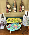 Daffodil Terra Clay Paint provides endless possibilities for your imagination and can be used on wood, canvas, tile, fabric and more! 2 entertainment trays staged with various home decor items, one is blue with transfers and the other is painted in daffodil with transfers as well.