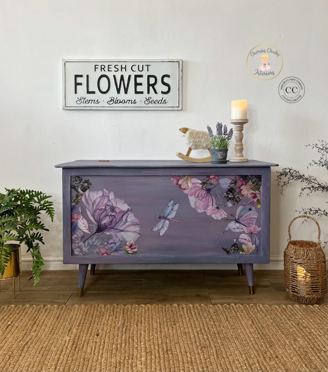 Elderberry Terra Clay Paint provides endless possibilities for your imagination and can be used on wood, canvas, tile, fabric and more! Purple clay painted chest with legs, Translucent Garden rub on furniture Transfer applied on the front of the chest. Large metal "Fresh Cut Flowers, Stems, Blooms, Seeds" sign on the wall over the piece. Metal vase with lavender flowers, and a beige candlestick on top.