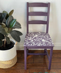 Elderberry Terra Clay Paint provides endless possibilities for your imagination and can be used on wood, canvas, tile, fabric and more! Purple clay painted chair with the Songbirds stencil applied in white paint. Large rubber plant in a white woven basket next to the chair.