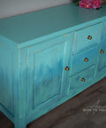 Lani's Lagoon Terra Clay Paint provides endless possibilities for your imagination and can be used on wood, canvas, tile, fabric and more!
Entertainment center cabinet painted in Lani's Lagoon Terra Clay Paint  as well as Blue Agave, Cerulean Blue Terra Clay Paint, Blue Moon and Malachite used in layers and a gradient between the colors. Staged on a white wall and gray floors.