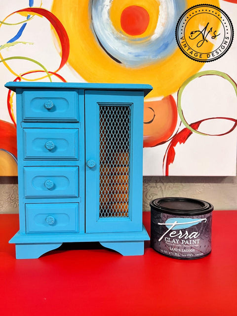 Lani's Lagoon Terra Clay Paint provides endless possibilities for your imagination and can be used on wood, canvas, tile, fabric and more!
Jewelry box painted in Lani's Lagoon Terra Clay Paint Staged on top of a red platform  and the 16 ounce container of Lani's Lagoon Terra Clay Paint besides piece.