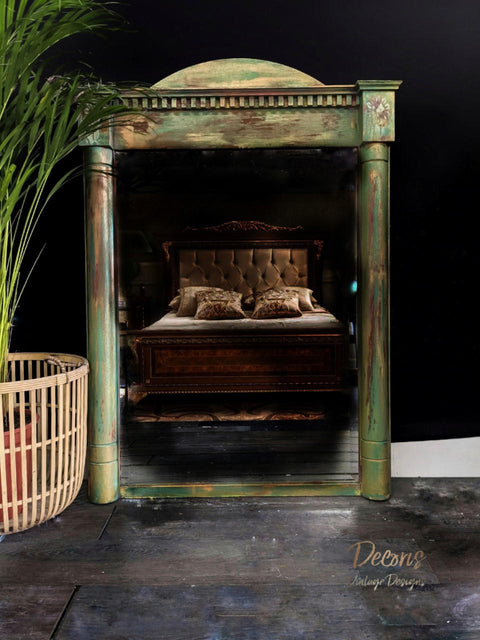 Malachite Terra Clay Paint provides endless possibilities for your imagination and can be used on wood, canvas, tile, fabric and more!
Large full body wide mirror painted with a blend of Malachite Terra Clay Paint, bronze, copper, and streaks of blue. Staged on the floor of a dark room in front of a brown bed with pillows on top.