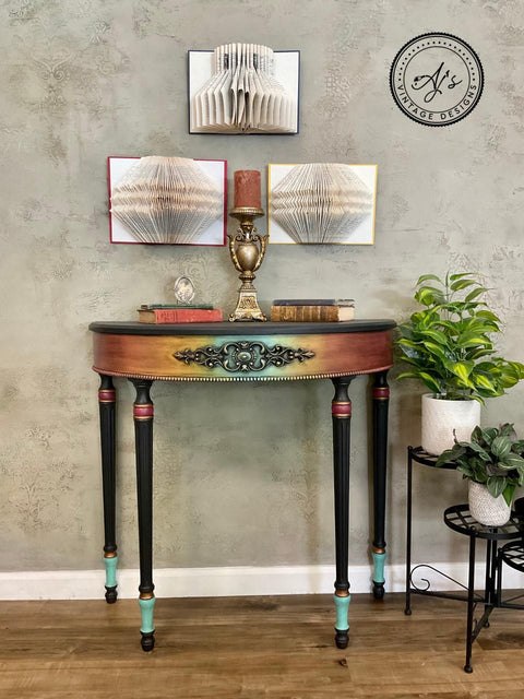 Marigold Terra Clay Paint provides endless possibilities for your imagination and can be used on wood, canvas, tile, fabric and more! End table painted Rainbow Ombre with Terra Clay paint. Staged with book with candle sticks and candles on top and some plants in white pots besides it.