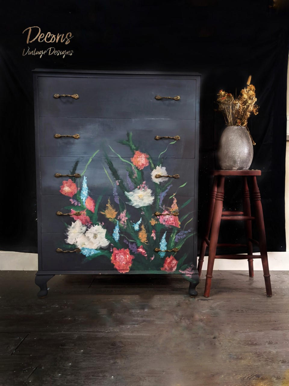 Onyx Terra Clay Paint provides endless possibilities for your imagination and can be used on wood, canvas, tile, fabric and more! Black clay painted dresser with red, white, blue, purple and orange flowers painted on it. Staged next to a red stool with vase and flowers on top of it.