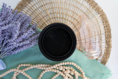 Onyx Terra Clay Paint provides endless possibilities for your imagination and can be used on wood, canvas, tile, fabric and more! Black clay paint open top view staged with lavender, wicker place mat and a wood beads.