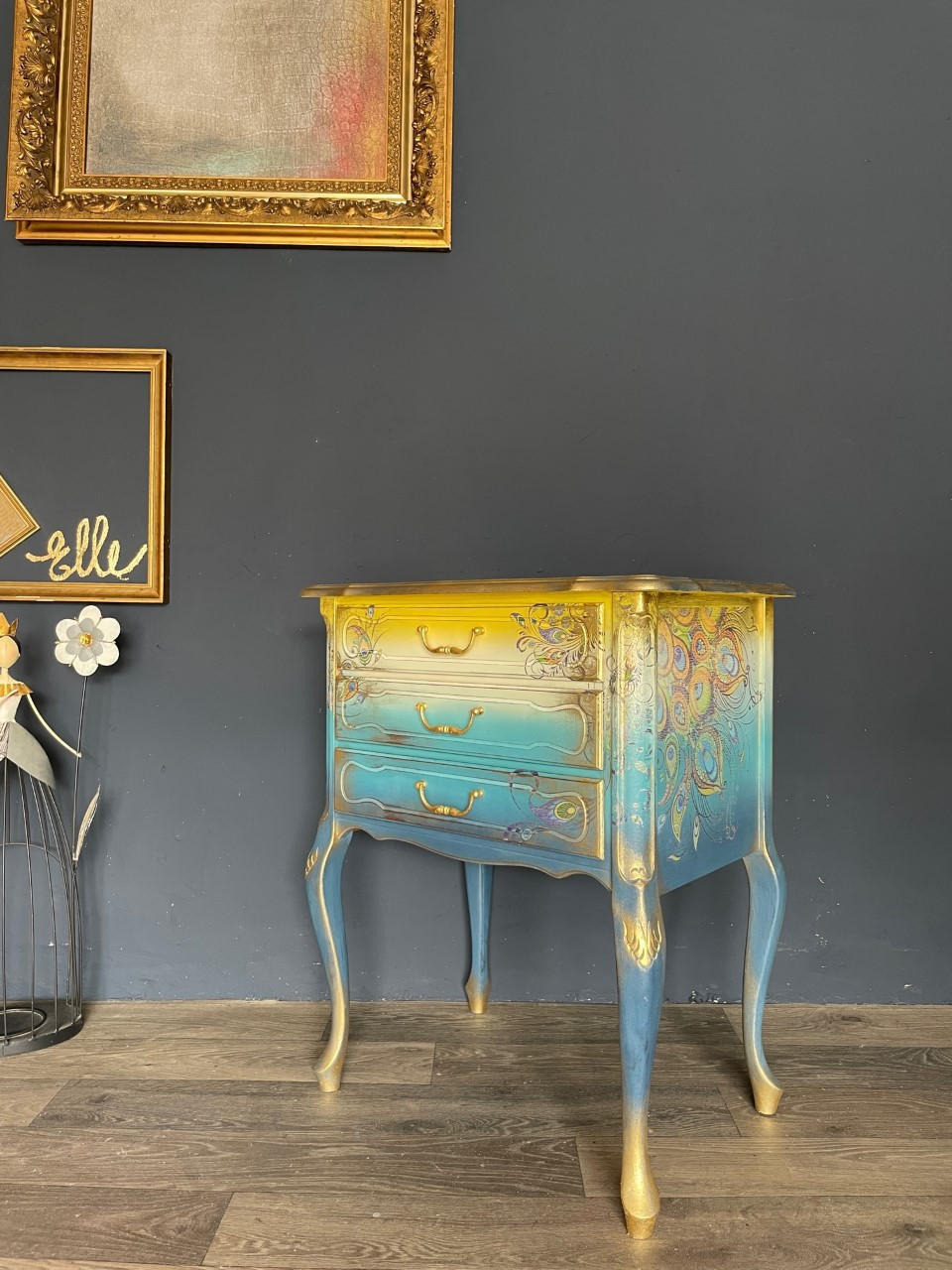 Prairie Dawn Terra Clay Paint provides endless possibilities for your imagination and can be used on wood, canvas, tile, fabric and more! Clay painted end table in yellow, cream, light blue and dark blue with gold on the feet and trim, and a peacock rub on transfers.