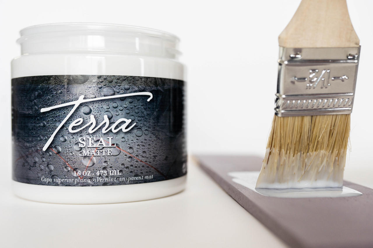 Terra Clay Paint Terra Seal - Jar of Terra Seal clay paint sealer sitting on table without lid sitting next to a paint brush applying Terra Seal to a piece of wood.