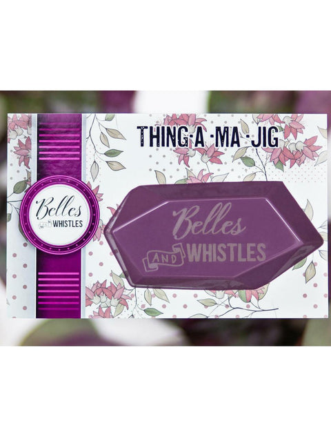 Belles and Whistles Thing-a-ma-jig - Thing-a-ma-jig in it's packaging with a purple, green and white blurred background