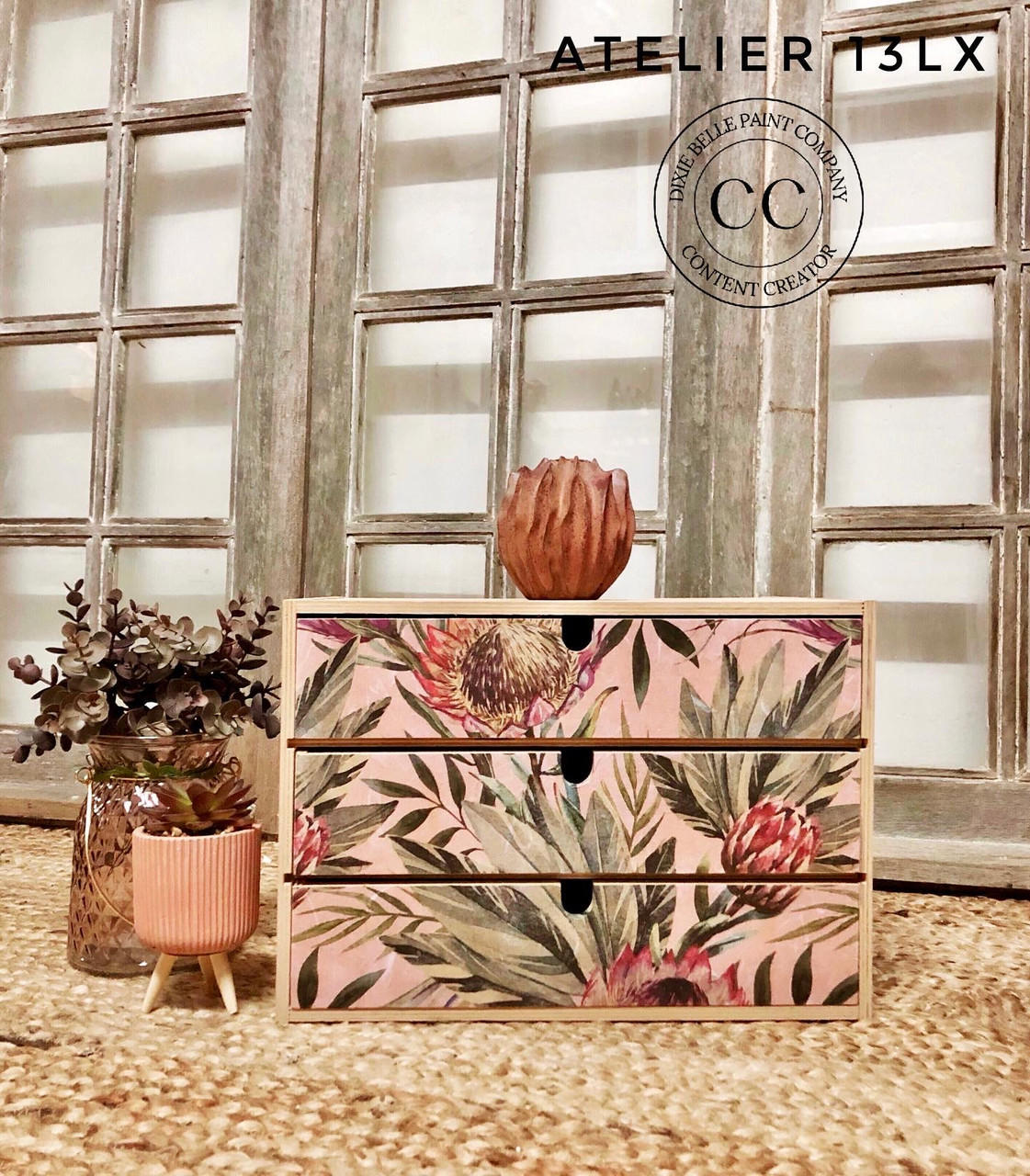 Belles and Whistles Tropical on Pink - Rice Decoupage Paper.  Small chest of drawers with the tropical On Pink Rice Decoupage Paper on front, staged with two planters on the left, one with cactus and one with dried floral arrangement