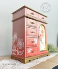 Pink painted jewelry box/chest with gold handles and accents. The Wildflowers Silkscreen Stencil has been applied in white on the front and side.