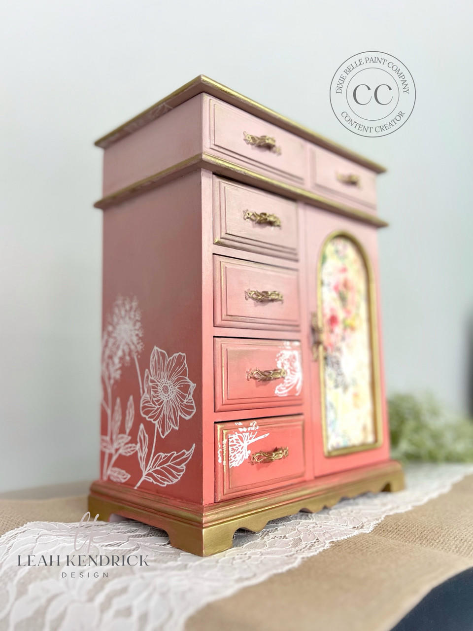 Pink painted jewelry box/chest with gold handles and accents. The Wildflowers Silkscreen Stencil has been applied in white on the front and side.