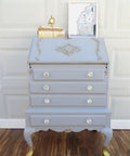 WoodUBend Applique #1245.26 (set of 2) is the perfect mouldable embellishment for any project! Applique #1245.26 set on top of light blue chalk painted dresser with angled opening top. The dresser is embellished with other Wood U Bend designs such as keyhole and has gold feet.