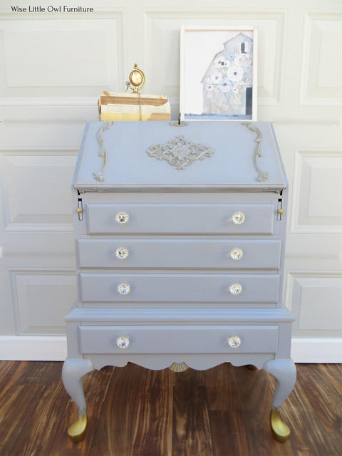 WoodUBend Applique #1245.26 (set of 2) is the perfect mouldable embellishment for any project! Applique #1245.26 set on top of light blue chalk painted dresser with angled opening top. The dresser is embellished with other Wood U Bend designs such as keyhole and has gold feet.