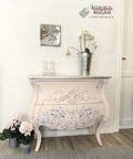 WoodUBend Applique #1245.26 (set of 2) is the perfect moludable embellishment for any project! Applique #1245.26 set on the face of a pink chalk painted dresser. The molds have been cut and placed separately so that the drawers can open. The piece is staged in a white room with pink flowers.