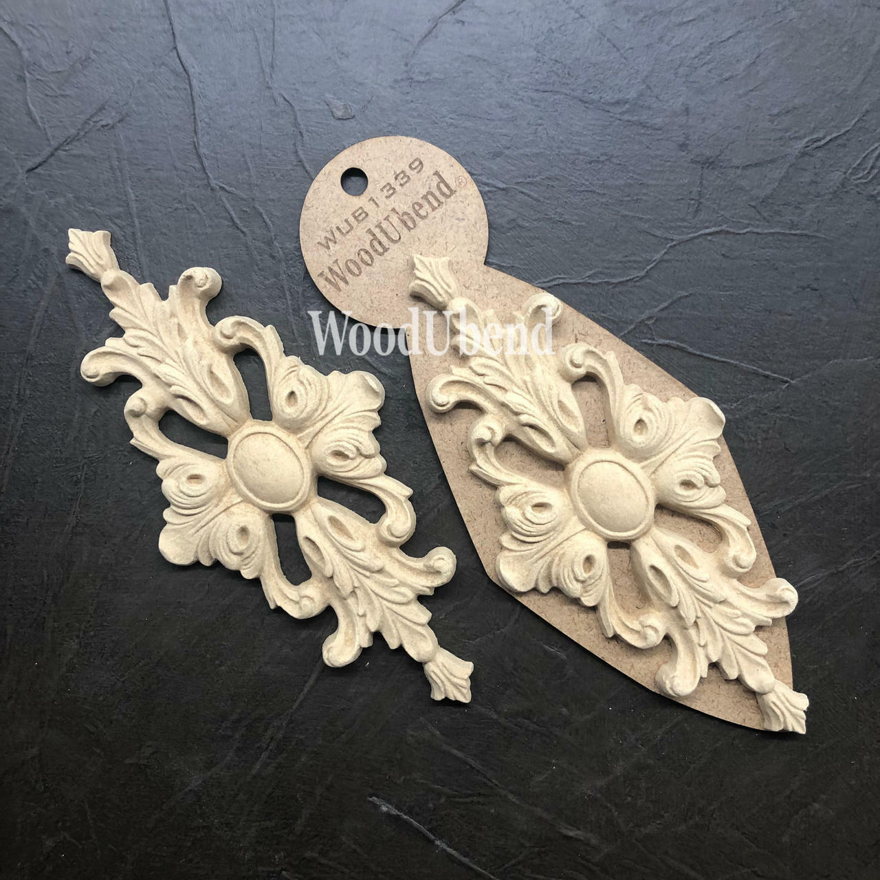 WoodUBend Applique #1339 (Set of 2) is the perfect mouldable embellishment for any project! Applique #1339 (Set of 2) with packaging against black background.