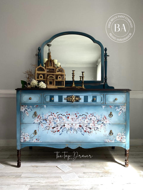 WoodUBend Applique #1339 (Set of 2) is the perfect mouldable embellishment for any project! Image of one Applique #1339 applied to light blue multi toned chalk mineral painted dresser. The appliques and hardware are finished in a bronze color. The dresser is also finished with a floral pattern painted on the front.