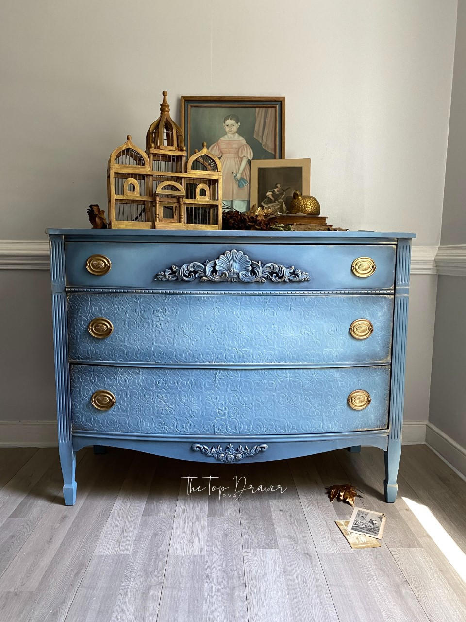WoodUBend Applique #1372.48 (Set of 2) is the perfect mouldable embellishment for any project! This piece features Applique #1372.48 (Set of 2) mounted to the top drawer of a dresser painted with Blue Dixie Belle Chalk Mineral Paint. This piece is staged with various gold accents.