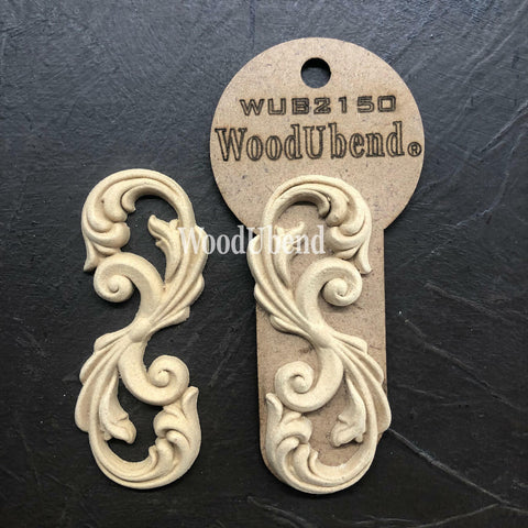 WoodUBend Applique #2150 (Set of 2) is the perfect mouldable embellishment for any project!
The Applique #2150 (Set of 2) is seen with one in a packaging and one without, staged on top of a black crinkled background.