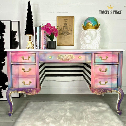 Applique #2152 Set of 2 is the perfect mouldable embellishment for any project!
A whimsical vanity with a rainbow cloudy effect, on the center drawer you can see Applique #2152 painted in gold in between the gold hardware.