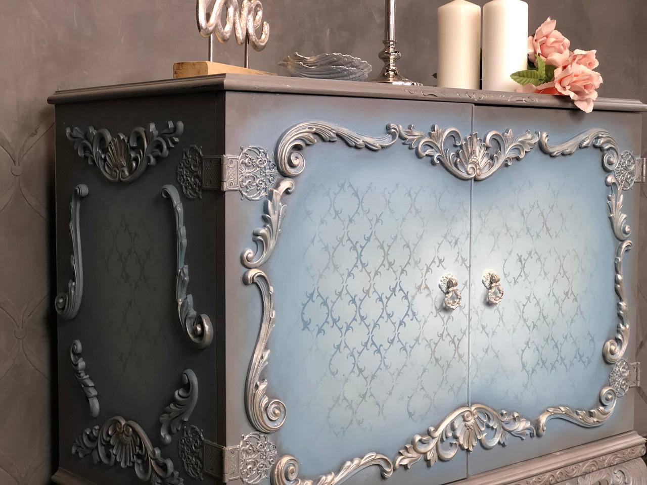 Applique #2152 Set of 2 is the perfect mouldable embellishment for any project!
A bar cabinet with woodwork around the front of the doors as well as the side of the cabinet you can see Applique #2152 Set of 2 on the top and bottom center of the cabinet as well as the side panel on the top and bottom.