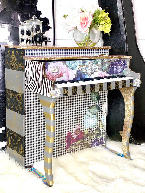 WoodUBend Applique #2447 (set of 2) is the perfect mouldable embellishment for any project!
A vintage piano with Applique #2447 (set of 2) on either sides of the keyboard. Staged on white fur carpet and a black guitar box besides the piece.