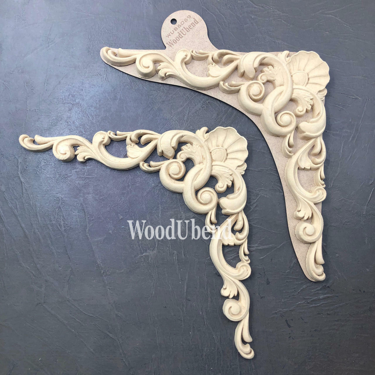 WoodUBend Applique #6069 (Set of 2) is the perfect mouldable embellishment for any project!
There are two Appliques in this picture.  The are identical.  These would be perfect to a corner embellishment because they are curved like a corner.  In the top of the bend there is a "sea shell" design.  From the bottom of the shell there looks like two waves  going in either direction of each other.  From that there are other wave looking frills.  The length of each side looks to be about 3 inches long.