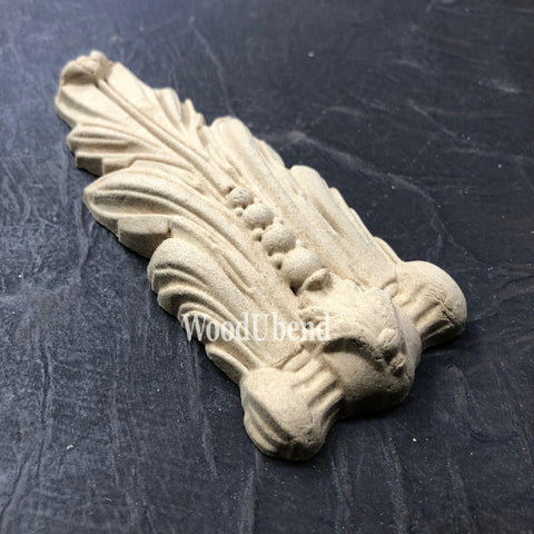 WoodUBend Applique #6076 (Set of 2) is the perfect mouldable embellishment for any project!
One of the Applique #6076 (Set of 2) out of the packaging and upside down staged on a black crinkled background.