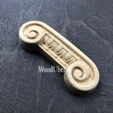 WoodUBend Applique #6081 (Set of 2) is the perfect mouldable embellishment for any project! 
One of the Applique #6081 (Set of 2) is seen flat and facing to the left. Staged on a black crinkled background.