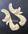 WoodUBend Applique #6096 (set of 2) is the perfect mouldable embellishment for any project!
The  Applique #6096 (set of 2) is seen side by side out of their packaging on a black crinkled background.