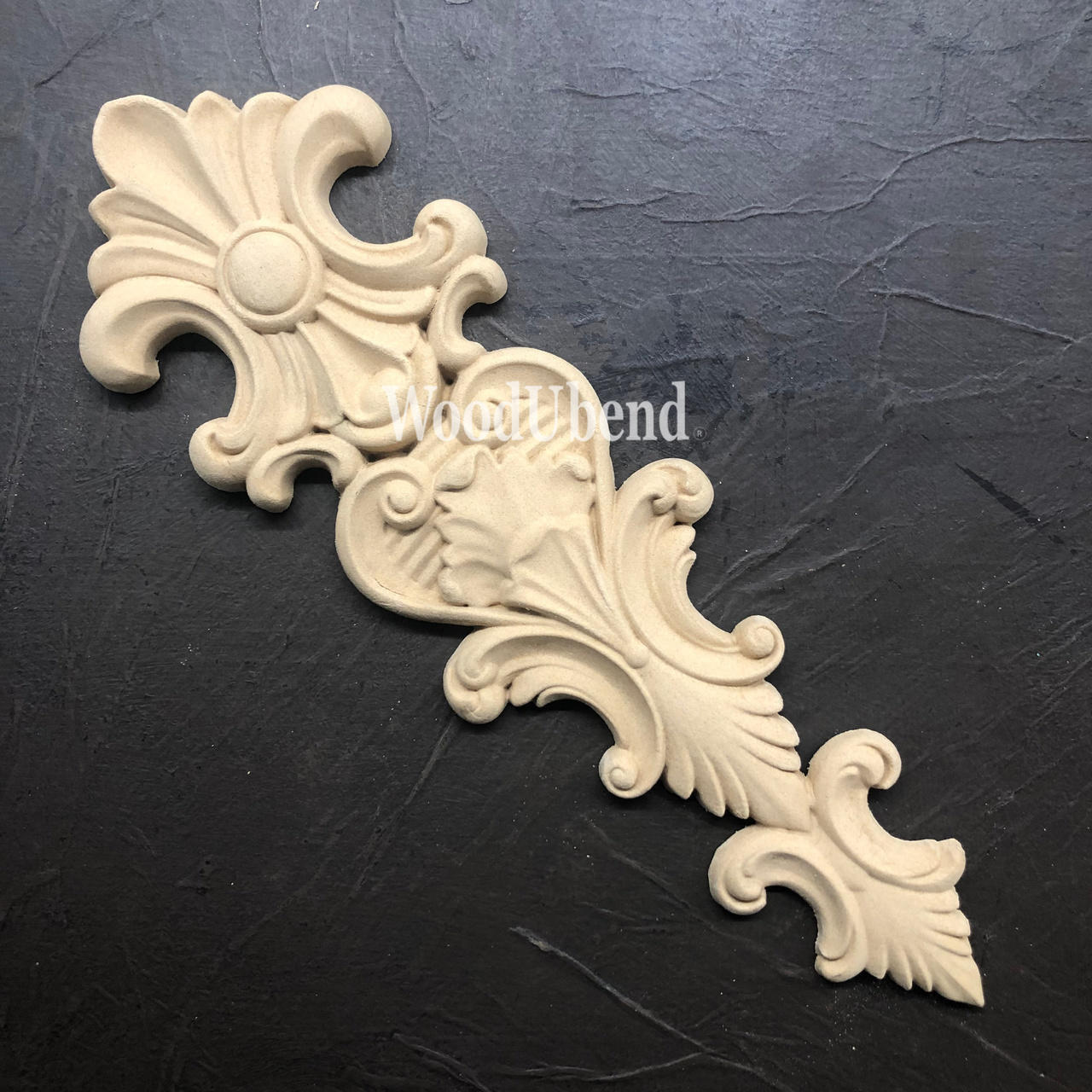 WoodUBend Applique #X1002 is the perfect moldable embellishment for any project!
The Applique #X1002 is seen displayed flat and staged on a black crinkled background.