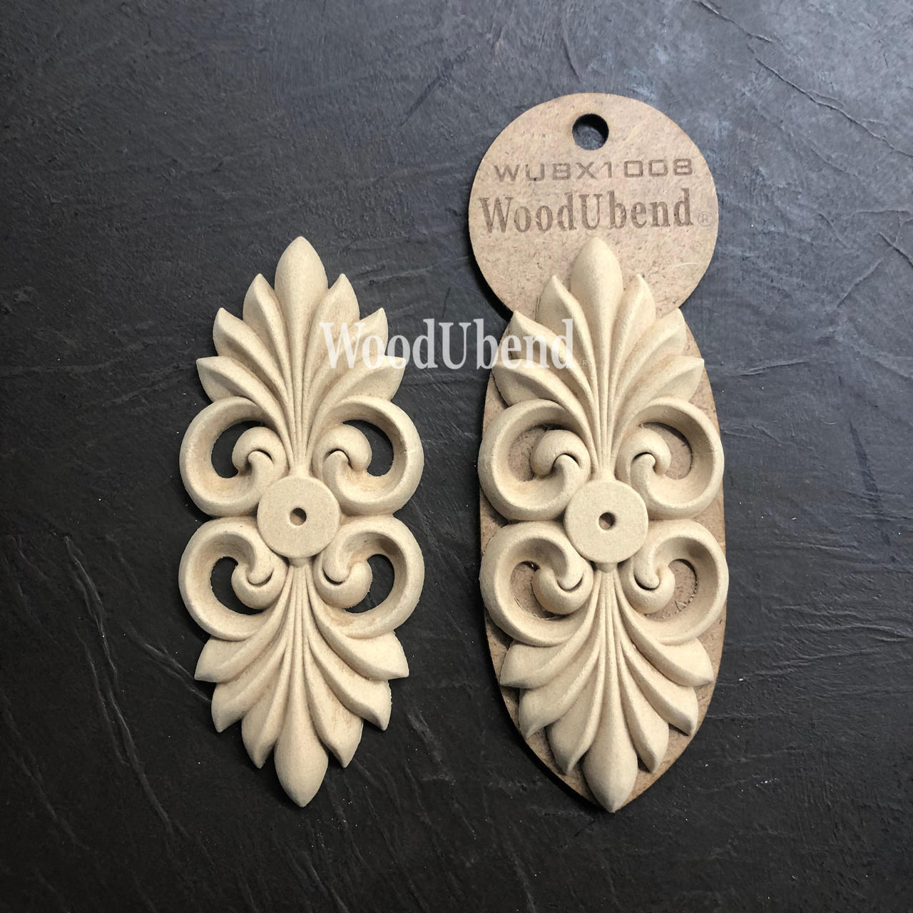 WoodUBend Applique #X1008 is the perfect mouldable embellishment for any project!
The Applique #X1008 is seen in its packaging and another side by side without packaging. Staged flat on top of a black crinkled background.