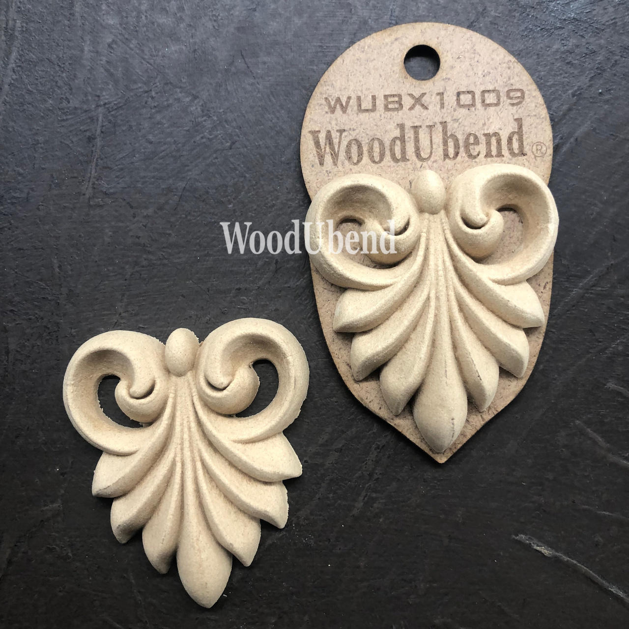 WoodUBend Applique #X1009 is the perfect mouldable embellishment for any project!
Image of two Applique #X1009 is seen displayed flat and staged on a black crinkled background.