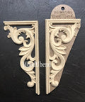 WoodUBend Corner Applique #2160 set of 2
There are two corner pieces from wood-u-bend.  They are facing away from each other.  One is out of the packaging and the other is still in the packaging.  There is a 90 degree frame around the Victorian curved and embellished piece. They are resting on black leather that fills the picture from edge to edge.
