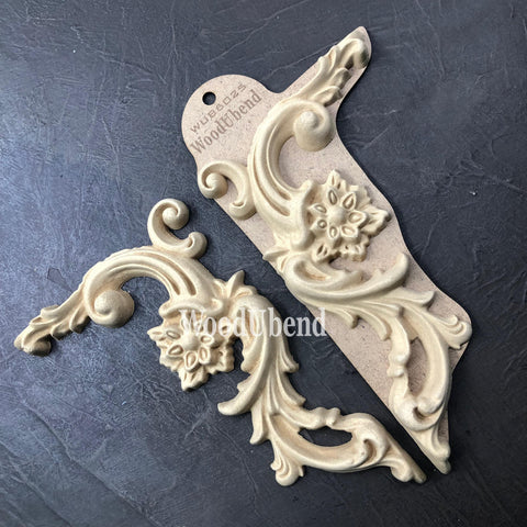 WoodUBend Corner Applique #6025 (set of 2) is the perfect mouldable embellishment for any project!
There are two corner woo-u-bend moldings resting on black leather.  One is out of the packaging and the other is still in the packaging.  They are facing away from each other.  They would be perfect for any DIY furniture project.