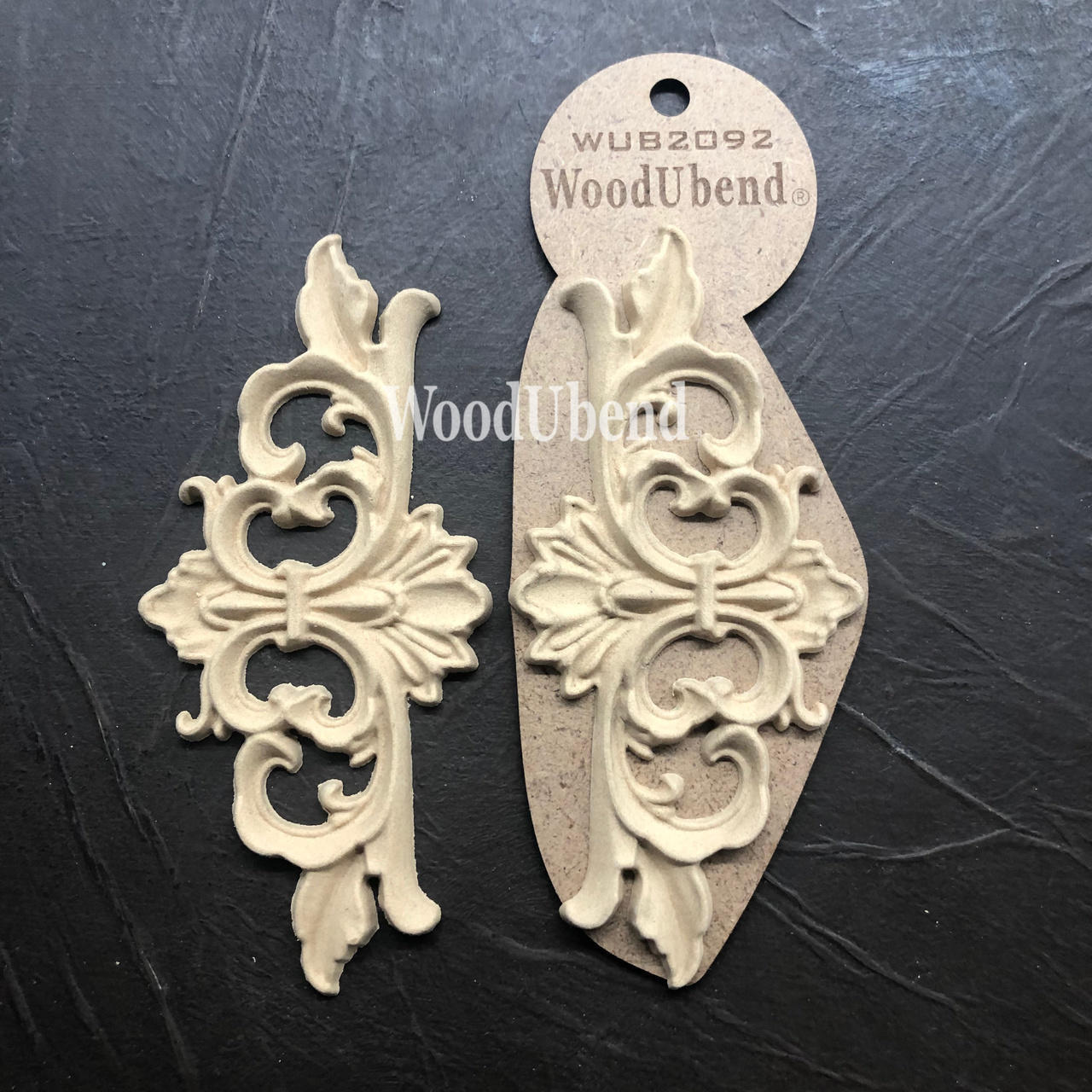 WoodUBend Fleur-de-lis Applique #2092 (set of 2) is the perfect mouldable embellishment for any project!
There are two Fleur-de-lis Appliques in this picture.  One is out of the packaging and one is still in the packaging.  They are staged on black, leather.