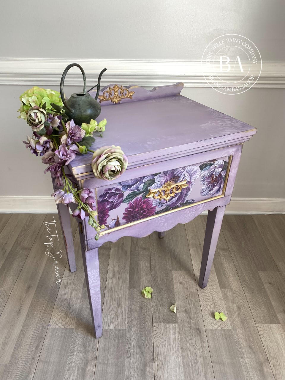 WoodUBend Fleur-de-lis Applique #2092 (set of 2) 
Here is a lavender table with flower decoupage on the front and a Fleur-de-lis applique in the center of the front and back lift.  It is staged with flowers and a watering pot.