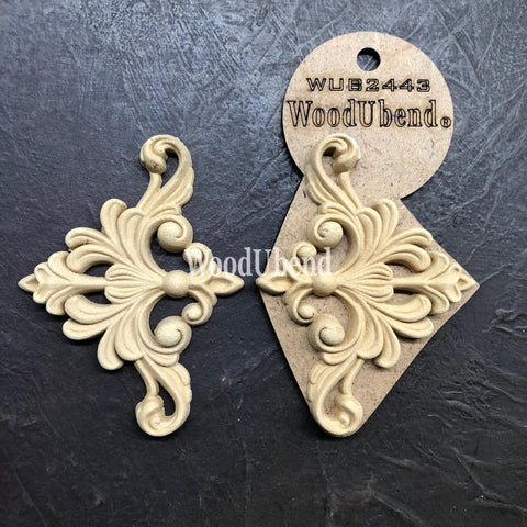 WoodUBend Fleur-de-lis Applique #2443 (set of 2) is the perfect mouldable embellishment for any project!
An image of the Fleur-de-lis Applique #2443 Set of 2 , one of them are in its packaging while the other is out facing each other. Staged on a black crinkled background.
