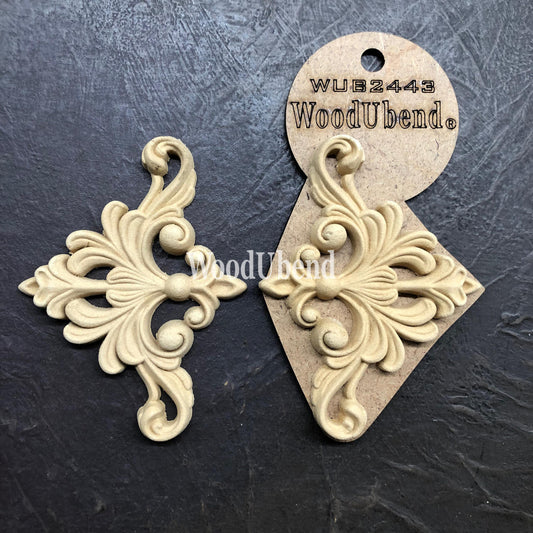 WoodUBend Fleur-de-lis Applique #2443 (set of 2) is the perfect mouldable embellishment for any project!
An image of the Fleur-de-lis Applique #2443 Set of 2 , one of them are in its packaging while the other is out facing each other. Staged on a black crinkled background.