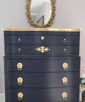 WoodUBend Fleur-de-lis Applique #2443 (set of 2) is the perfect mouldable embellishment for any project!
A black chest of drawers with the top, legs and as well as the hardware in gold. The Fleur-de-lis Applique #2443 on the bottom trim of the piece. Staged with a gold oval framed mirror.