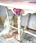 WoodUBend Floral Applique #1479 (Set of 5) is the perfect mouldable embellishment for any project!
A white console table with Floral Applique #465, Floral Applique #319 and Floral Applique #1479 in a bunch on the front center of the table at the top of the leg. Staged with a magazine and a woven bag with a white blanket over the bag under the table.